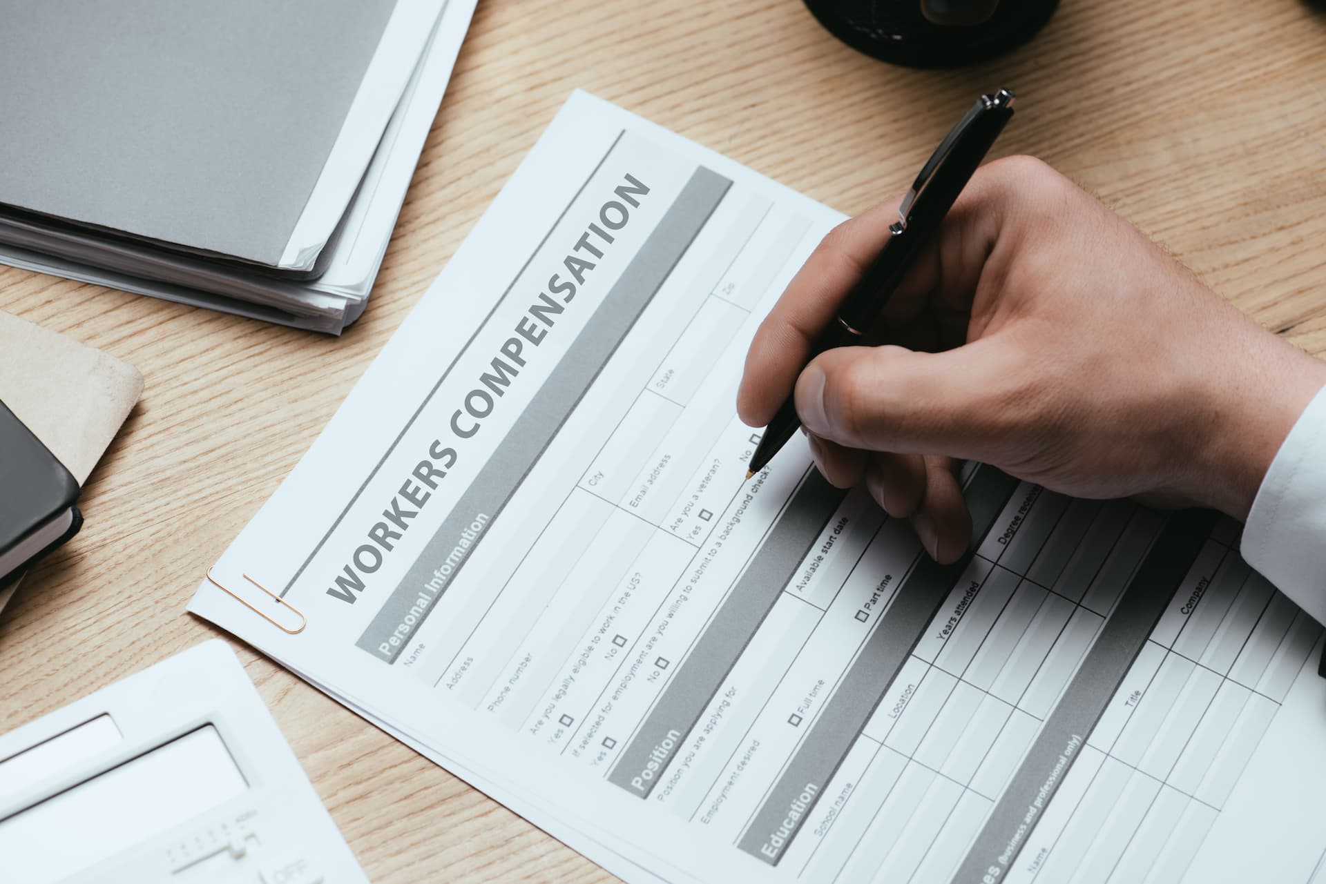 cropped-view-of-man-filling-in-workers-compensation-paperwork-opt workers comp settlement